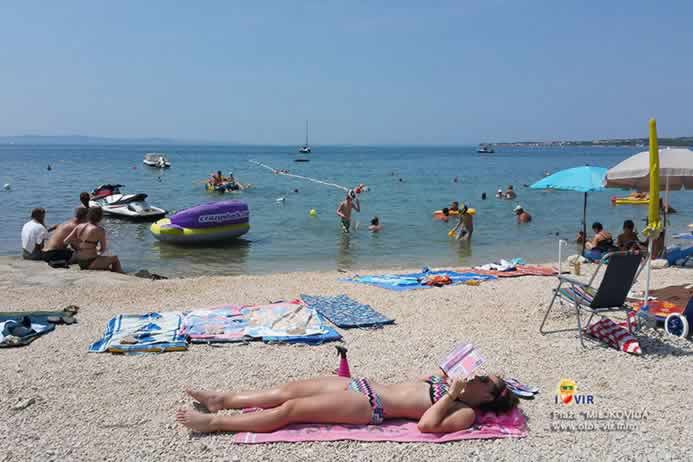 Djevojka čita knjigu na sunčanoj plaži uz more