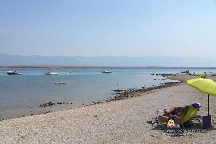 Uživanje na šljunčanoj plaži ispod suncobrana i mirno more