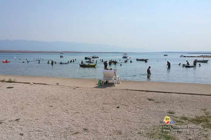 Šljunčano betonska plaža i kupaći u plitkom moru