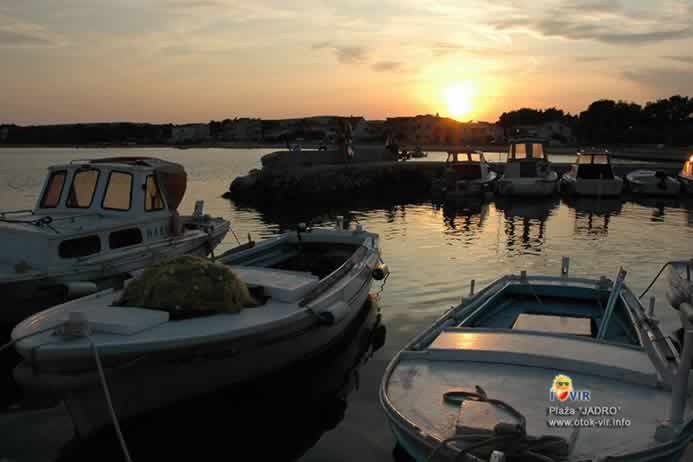 Sunčani zalaz u lučici s čamcima na plaži Jadro na Viru