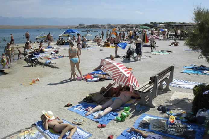 Turisti se sunčaju na šljunčanoj plaži pored mora