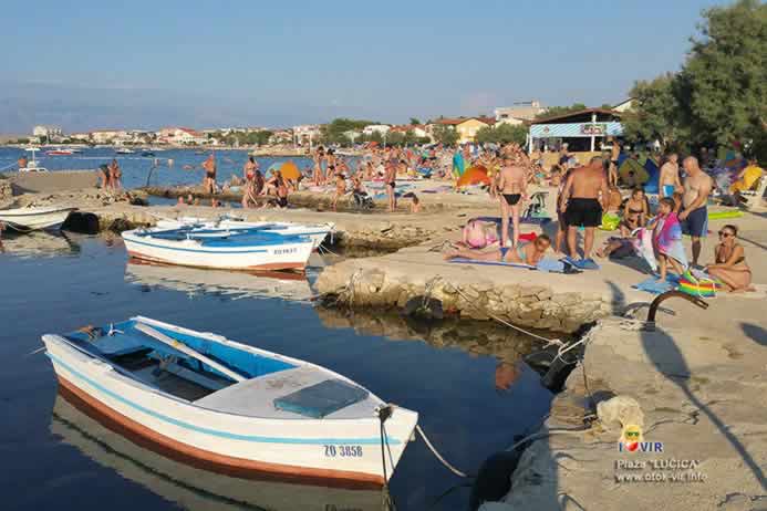 Bijela barka usidrena u lučici za brodove pored plaže za kupanje