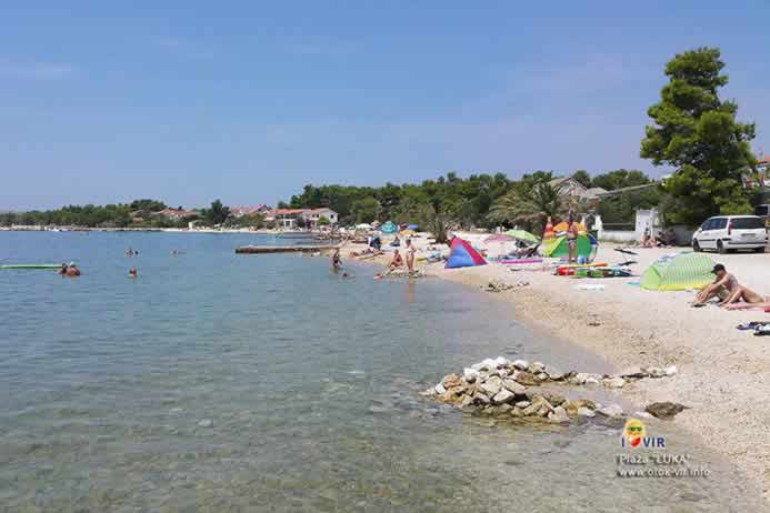 Kupači i rekviziti za kupanje na šljunčano pješčanoj plaži uz more