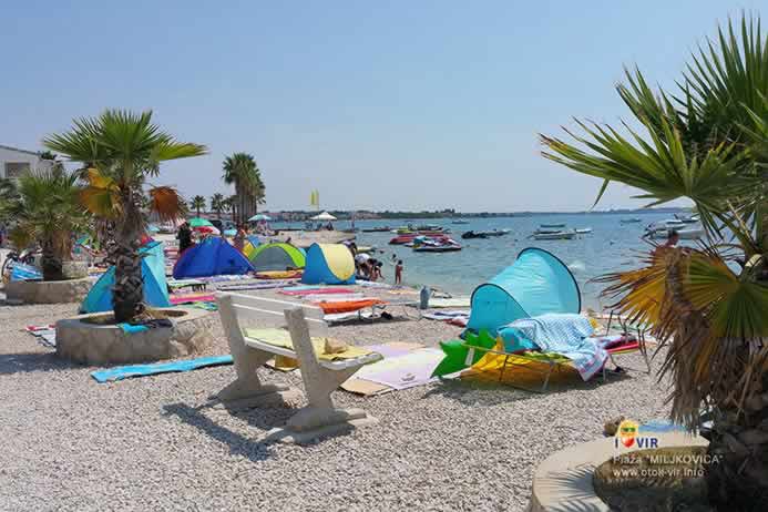 Bijela klupa i rekviziti za sunčanje na sunčanoj plaži