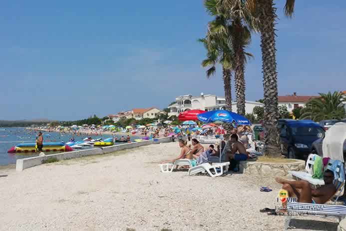 Odmor na plastičnim ležaljkama za sunčanje ispod palma na plaži