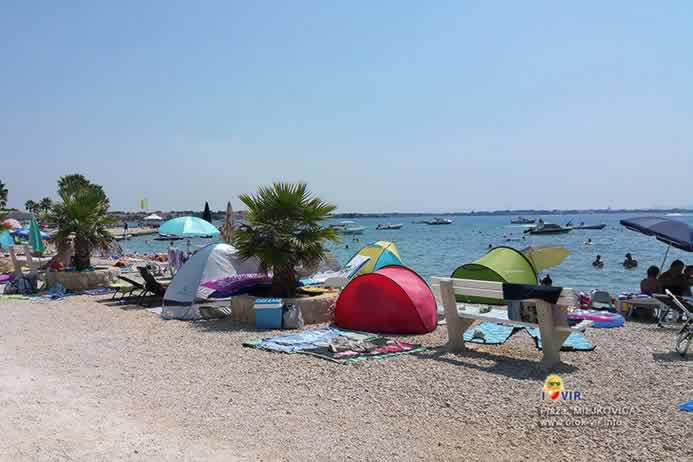 Ljetna sunčana plaža prepuna rekvizita i turista