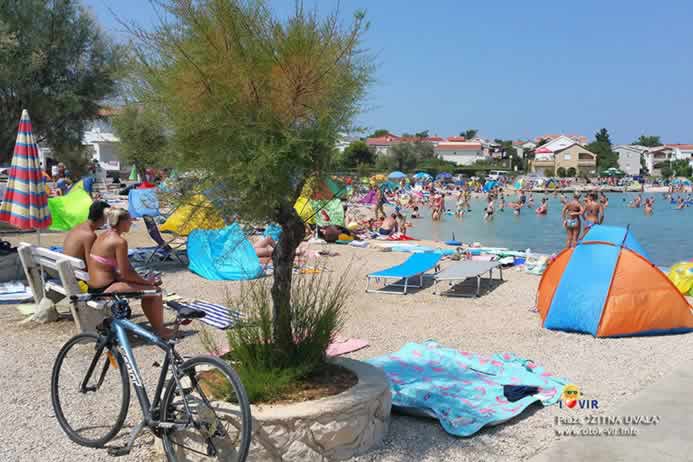 Bicikl naslonjen na kemenu žardinjeru i tamarisom uz more i plažu