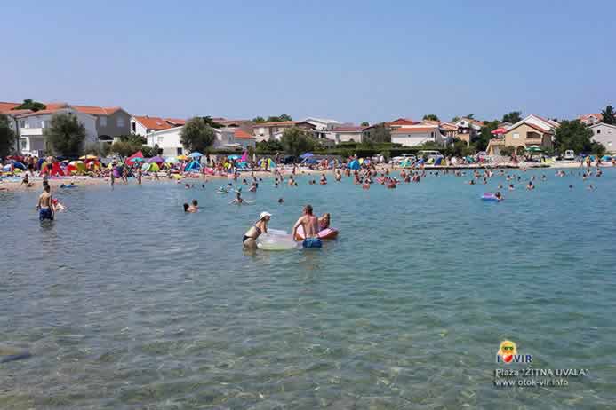 Kupači u moru i kuće u pozadini plaže